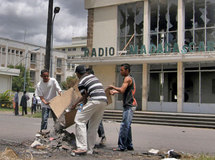 Devant le siège de la radio nationale incendié par des émeutier, des Malgaches nettoient des débris, le 29 janvier 2009.( Photo : Reuters )