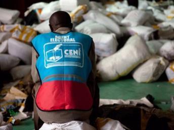 Kinshasa, 3 décembre 2011. Un agent électoral de la Céni au milieu des sacs de bulletins de vote. © AFP / Gwenn Dubourthoumieu