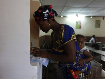 Une électrice avec son bébé sur le dos remplit son bulletin de vote, à Abidjan le 11 décembre 2011. REUTERS/Luc Gnago