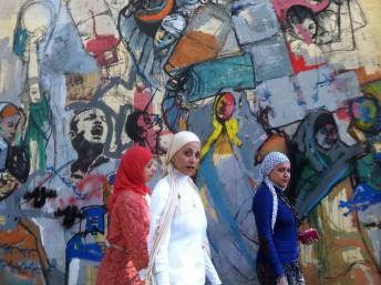 Des Egyptiennes passent devant une fresque peinte au Caire pendant la révolution. Photo RFI/Anne Corpet