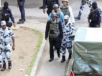 L'ancien général Brunot Dogbo Blé (c.) à son arrivée au tribunal, protégé par une escorte et un gilet pare-balles.