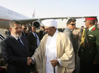 Le président soudannais Omar el-Béchir (à droite) accueillant le président Mohamed Morsi à son arrivée à Khartoum, ce jeudi 4 avril 2013. Photo AFP / Ashraf Shazly