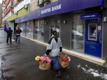 Une vendeuse de rue passe devant une agence bancaire à Bucarest, le 28 mars 2013.