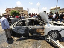 Le 6 août, à Benghazi, des passants entourent la carcasse d’une voiture détruite après l’explosion d’une bombe qu’elle transportait, tuant le conducteur. REUTERS/ Esam Omran Al-Fetori