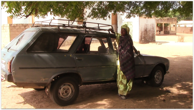 Maty qui se tient devant le véhicule qu'elle a acquis Maty qui se tient devant le véhicule qu'elle a acquis