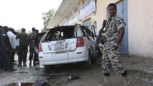 Un soldat somalien est posté à côté de la carcasse de la voiture du journaliste Yusuf Keynan, dans laquelle ce dernier se trouvait quand elle a explosé, le 21 juin 2014, à Mogadiscio. REUTERS/Feisal Omar