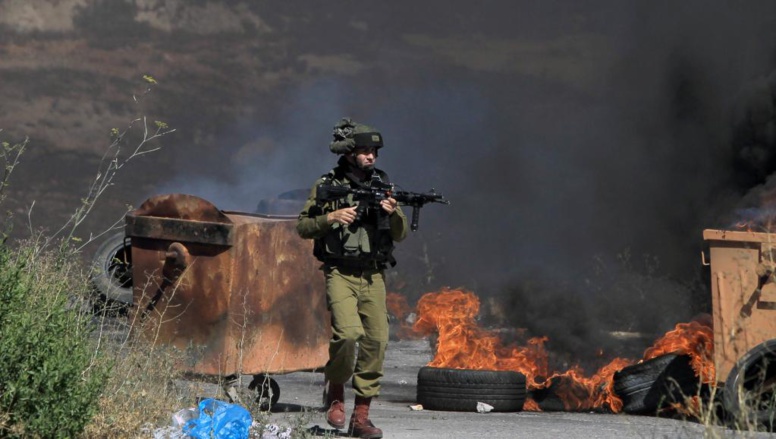 Un soldat israélien aux prises avec des manifestants palestiniens devant les portes de la colonie de Beit El en Cisjordanie, le 25 juillet 2014. AFP PHOTO / ABBAS MOMANI