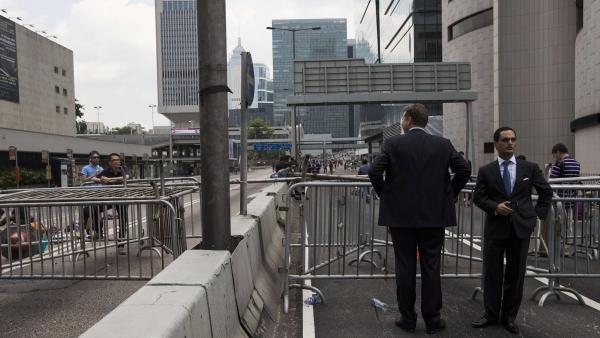 Des hommes d'affaires, devant une route bloquée par les manifestants pro-démocratie, en plein centre du quartier de la finance, à Hong Kong, ce lundi 29 septembre, au matin. REUTERS/Tyrone Siu