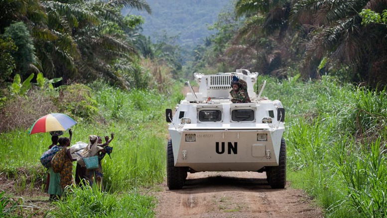 Des membres de la population locale, saluant le passage d’un véhicule blindé de transport de troupes de la Monusco, qui se dirige dans la région de Beni, province du Nord Kivu en RDC, le 13 mars 2014.
