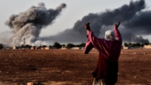 A la frontière turque, une femme contemple la ville kurde syrienne de Kobane après une frappe de la coalition, le 13 octobre 2014. Le bilan de ces raids aériens est au menu de la réunion de Londres, ce 22 janvier.