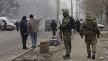 Des militaires ukrainiens en faction dans une rue de Marioupol, près du corps d'une vicitime des bombardements, le 24 janvier 2015. REUTERS/Nikolai Ryabchenko