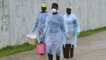 Des volontaires transportent des seaux de désinfectant jusqu'au centre de traitement Ebola, à Monrovia, le 25 septembre 2014.