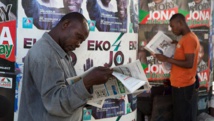 Des hommes lisent des journaux devant des affiches électorales, à Lagos, le 30 mars 2015. REUTERS/Joe Penney
