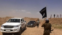Un membre du groupe Etat islamique brandit un drapeau de son organisation, près de la frontière irako-syrienne. ALBARAKA NEWS / AFP