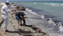 Des employés du Croissant-rouge libyen récupèrent le corps d'un migrant sur la plage de Zouara, le 28 août 2015, quelques heures après le naufrage du bateau. REUTERS/Hani Amara