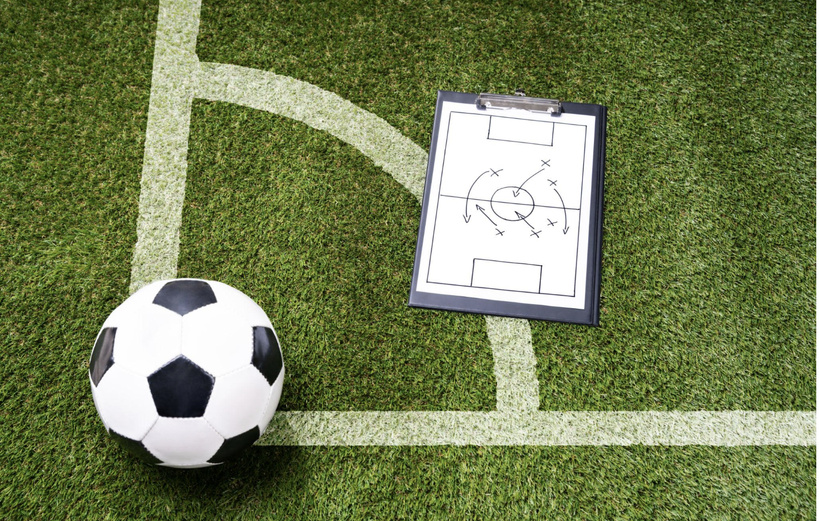 Ballon de football et tableau tactique sur une pelouse