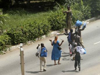 Des civils passent les mains en l'air devant un soldat fidèle à Laurent Gbagbo autour du palais présidentiel, à Abidjan le 3 avril 2011, pendant la crise postélectorale. REUTERS/Luc Gnago