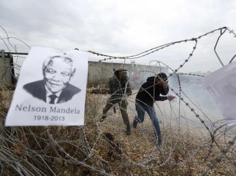 Un portrait de Nelson Mandela sur des fils barbelés lors d'une action contre la colonisation israélienne, près de Ramallah, le 6 décembre 2013. REUTERS/Mohamad Torokman