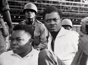 Patrice Lumumba (d.), le 30 juin 1960 à Leopoldville, aux côtés du vice-président du Sénat Joseph Okito, entourés de soldats. AFP PHOTO / STRINGER