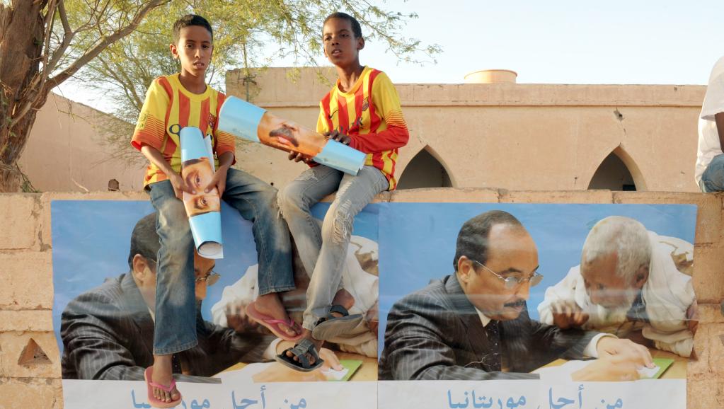 Akjout, le 18 juin 2014. Deux garçons tiennent en main des affiches de campagne du président sortant et candidat à un ssecond mandat Mohamed ould Abdel Aziz. AFP PHOTO / SEYLLOU