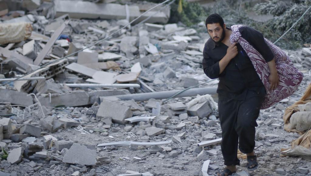 Un Palestinien évacue quelques affaires après un raid aérien israélien qui a détruit une maison à proximité de la ville de Gaza, le 16 Juillet 2014. REUTERS/Mohammed Salem