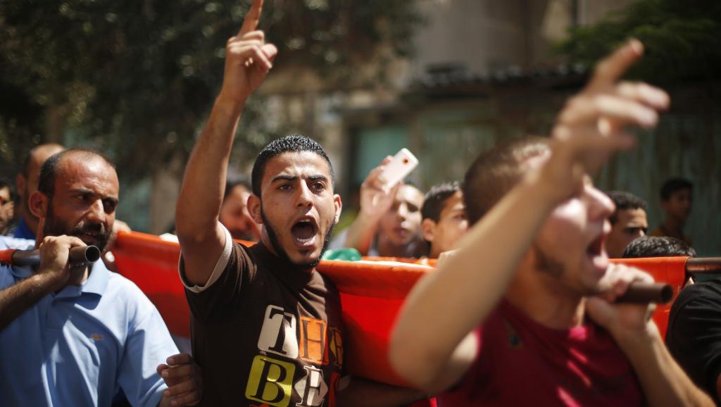 Des Palestiniens crient des slogans durant les funérailles de trois adolescents, tués durant l'offensive terrestre israélienne, à Gaza, le 18 juillet 2014. REUTERS/Mohammed Salem