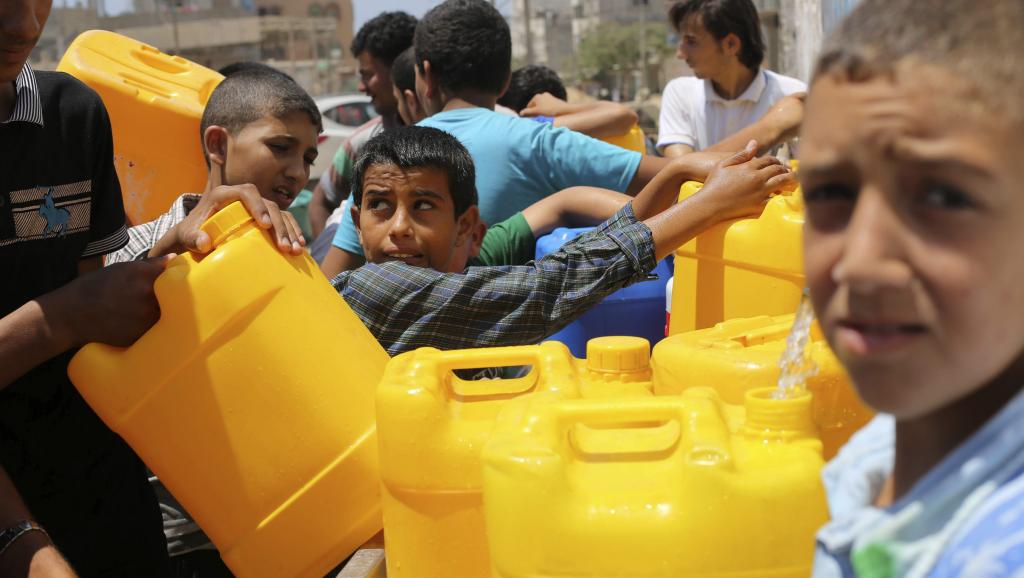 A Khan Younes (sud de la bande de Gaza) des jeunes Palestiniens profitent de la trêve humanitaire pour remplir des bidons d'eau.