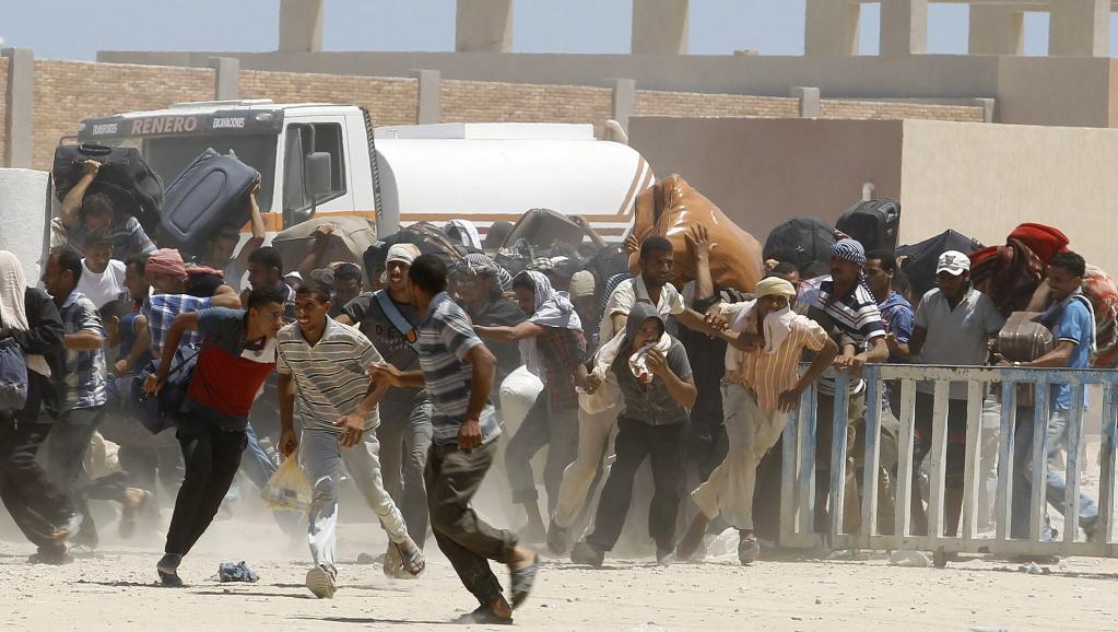 iens, lassés d'attendre, essaient de forcer le passage de la frontière tunisienne au poste de Ras Jedir, ce vendredi 1er août. Les policiers tunisiens tirent des grenades lacrimogènes pour les stopper. REUTERS/Zoubeir Souissi