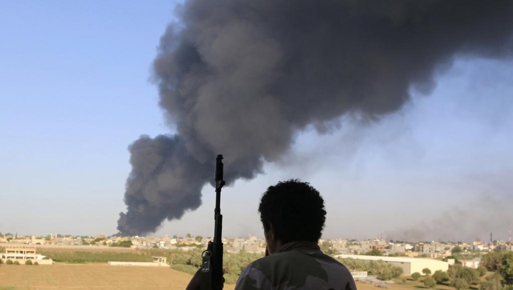 Un combattant de la milice de Zintan devant l'incendie d'un dépôt d'hydrocarbures à Tripoli, le 2 août 2014. REUTERS/Hani Amara