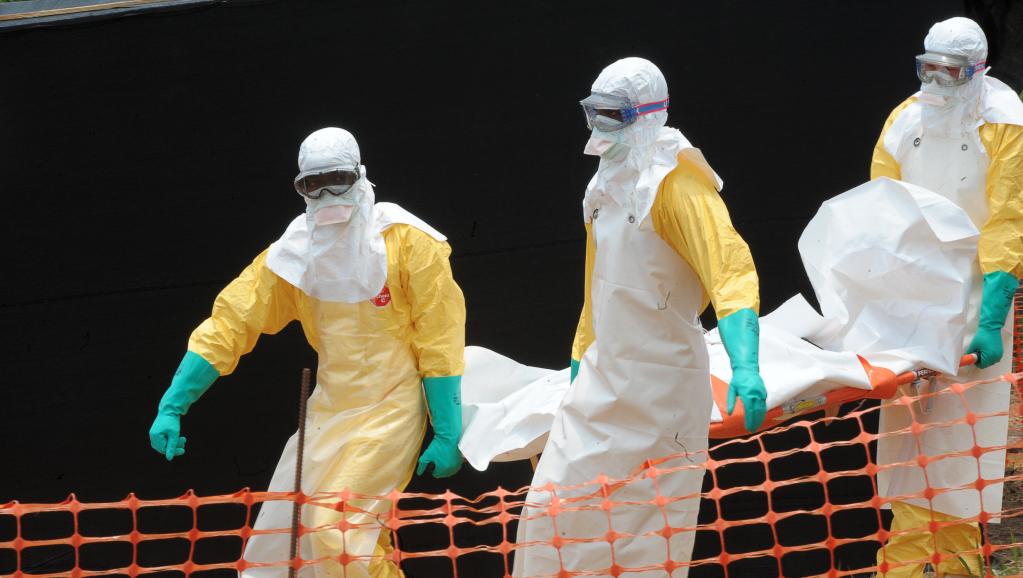 Du personnel de Médecins sans frontières porte le corps d'une personne décédée du virus Ebola, le 1er avril 2014, à Guekedou, en Guinée, dans un centre pour victimes de la fièvre hémorragique. AFP PHOTO / SEYLLOU