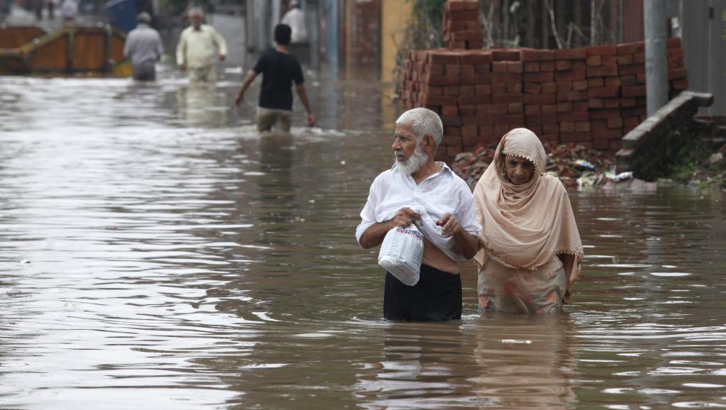 Un couple se déplace sur une route complètement submergée par les flots, le 4 septembre 2014 à Lahore. REUTERS/Mohsin Raza