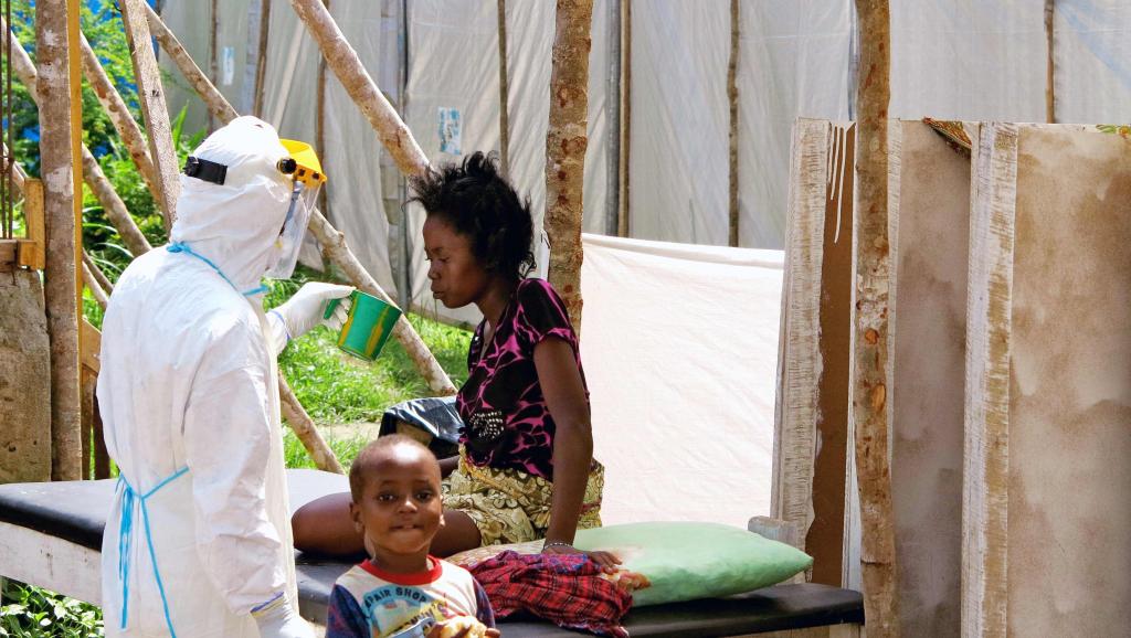 Un soignant donne à boire à une femme porteuse du virus Ebola, dans un centre de traitement spécialisé, à Kenema (Sierra Leone), en juillet 2014. REUTERS/Jo Dunlop/UNICEF/Handout via Reuters