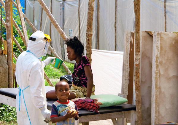 Un soignant donne à boire à une femme porteuse du virus Ebola, dans un centre de traitement spécialisé, à Kenema (Sierra Leone), en juillet 2014. REUTERS/Jo Dunlop/UNICEF/Handout via Reuters
