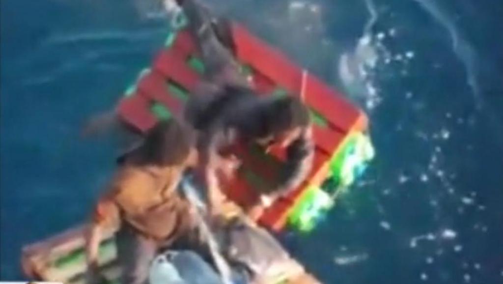 Cette image, tirée de la vidéo filmée par les marins, montre les deux personnes tentant de trouver l'équilibre sur de minuscules radeaux confectionnés par l'équipage du navire.