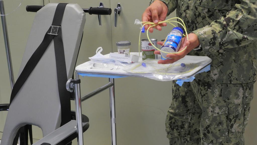 Un médecin militaire montre le matériel utilisé à Guantanamo pour forcer l'alimentation des prisonniers grévistes de la faim, le 7 août 2013. AFP PHOTO/Chantal Valery