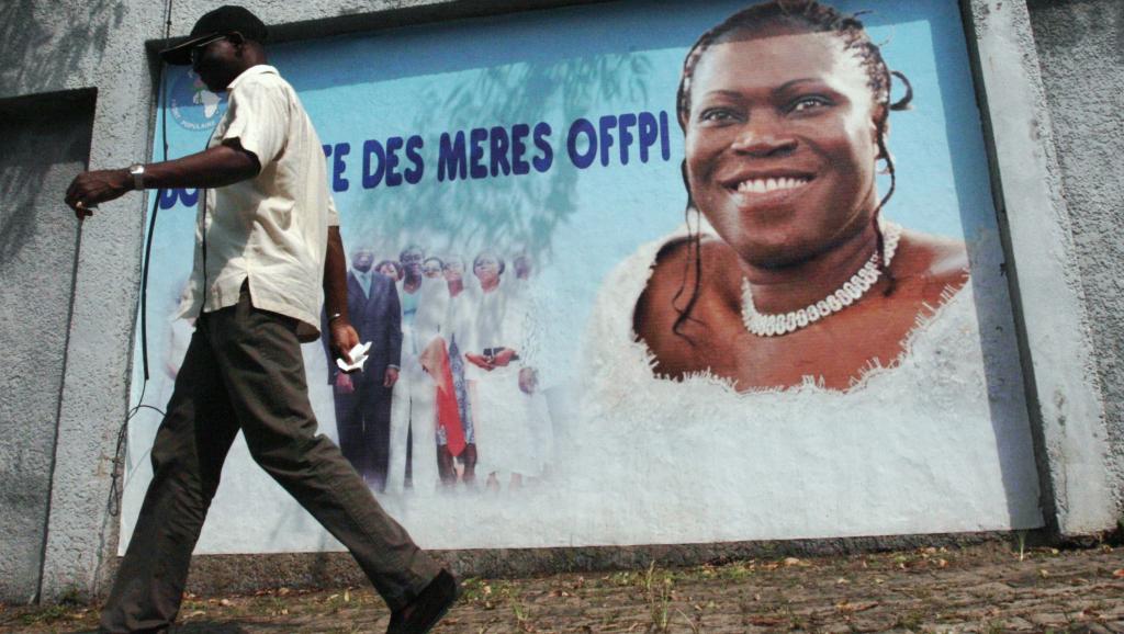 Un partisan du président déchu Laurent Gbagbo passe devant une affiche annonçant une conférence de presse de l'ex-première dame de Côte d'Ivoire Simone Gbagbo, en décembre 2013. AFP PHOTO / HERVE SEVI