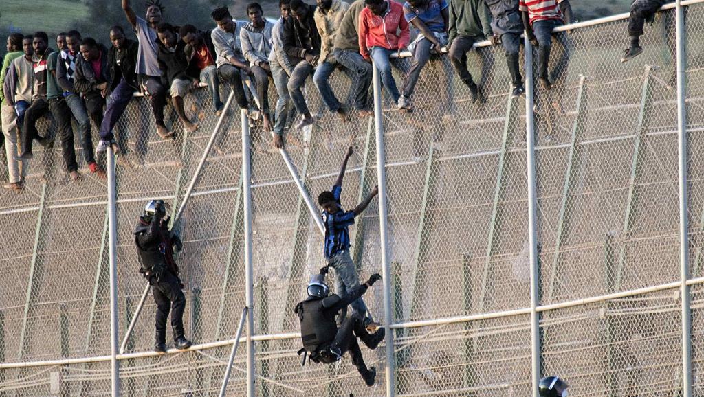 Des officiers de la Garde civile espagnole tentent d’arrêter les migrants africains qui veulent rejoindre l’Espagne par l’enclave de Melilla, en territoire marocain, le 15 octobre 2014. REUTERS/Jesus Blasco de Avellaneda