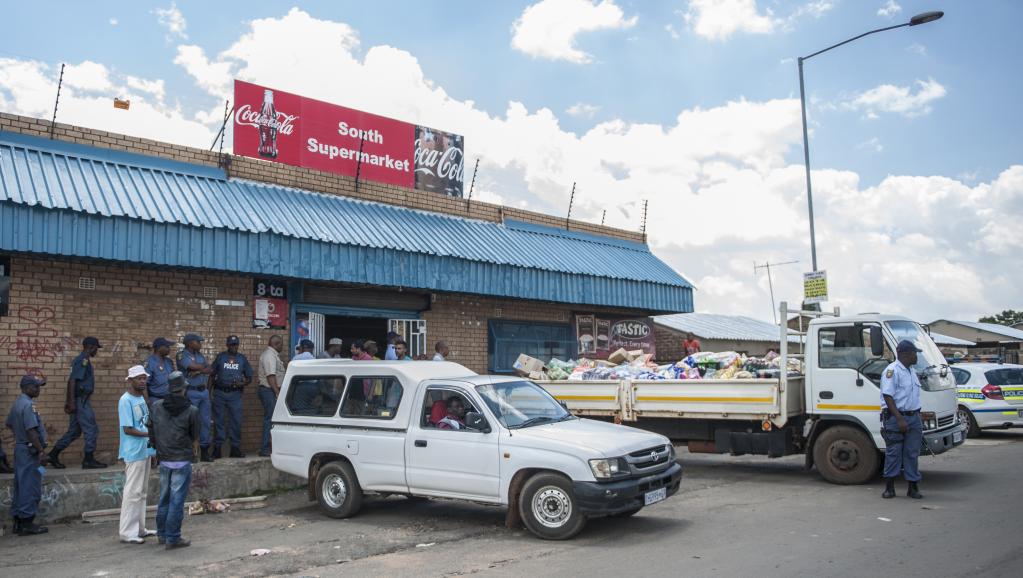 Des policiers sud-africains postés, le 23 janvier, devant un magasin tenu par des étrangers pour prévenir les vols à Kagiso, un bidonville à l'ouest de Johannesburg. AFP PHOTO/STEFAN HEUNIS
