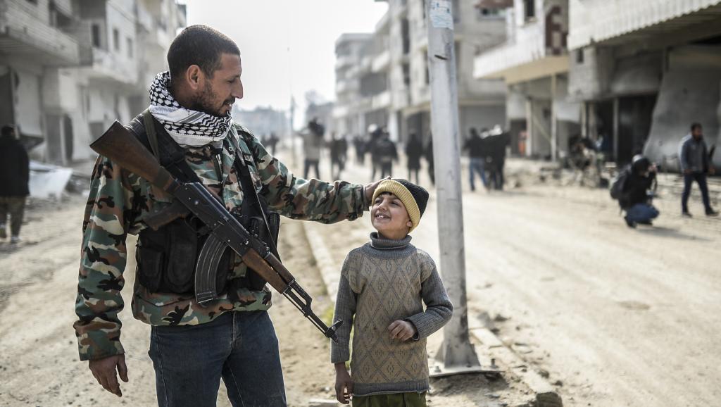 Un combattant des forces de défense kurdes avec un enfant à Kobane, en Syrie, le 28 janvier 2015. AFP PHOTO / BULENT KILIC