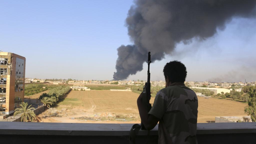 Un milicien regarde la colonne de fumée s'élever depuis un dépôt de carburant de l'aéroport de Tripoli, le 2 août 2014. REUTERS/Hani Amara