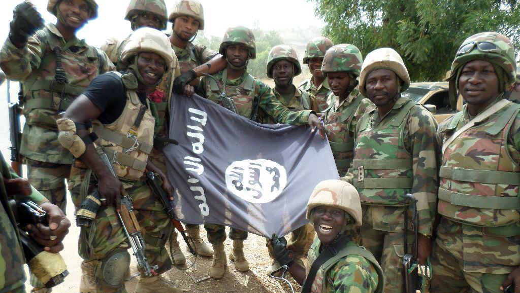 Des soldats nigérians posent devant le drapeau de Boko Haram après avoir démantelé un camp de la secte armée dans l'Etat du Yobe, en février dernier. AFP PHOTO/HO/NIGERIAN ARMY