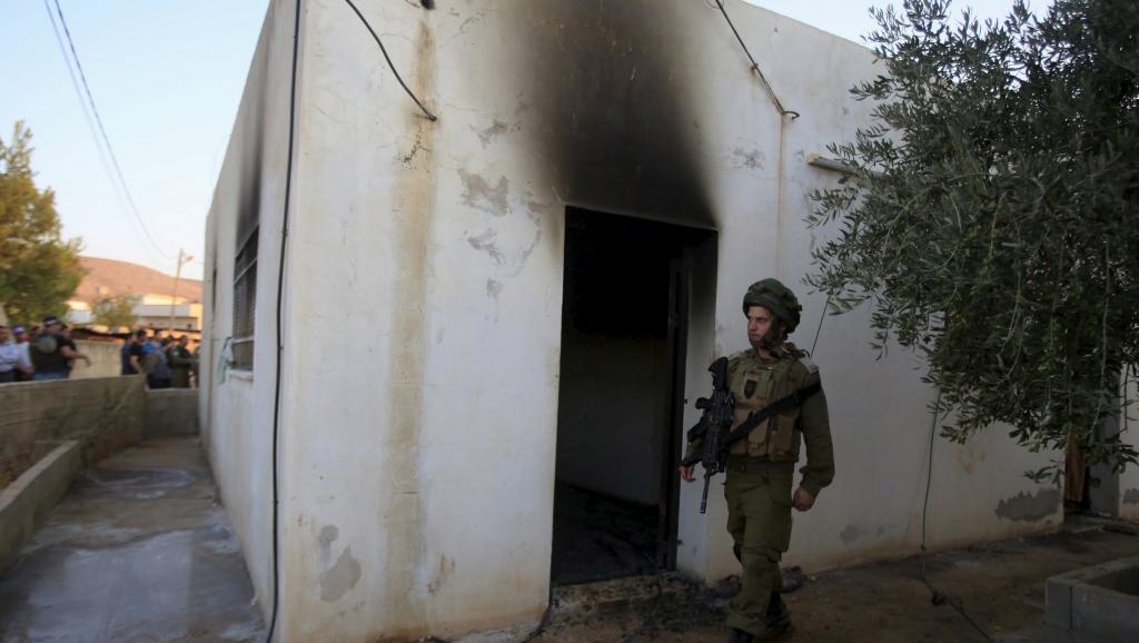Un soldat israélien devant la maison incendiée par des extrémistes juifs présumés où un enfant palestinien de 18 mois a été tué ce vendredi 31 juillet. REUTERS/Abed Omar Qusini