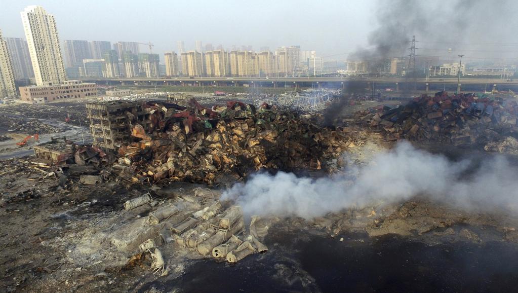 Le site de l'explosion à Tianjin d'où se dégagent encore des fumées, avec les habitations toutes proches en toile de fond, le 15 août 2015. REUTERS/Stringer