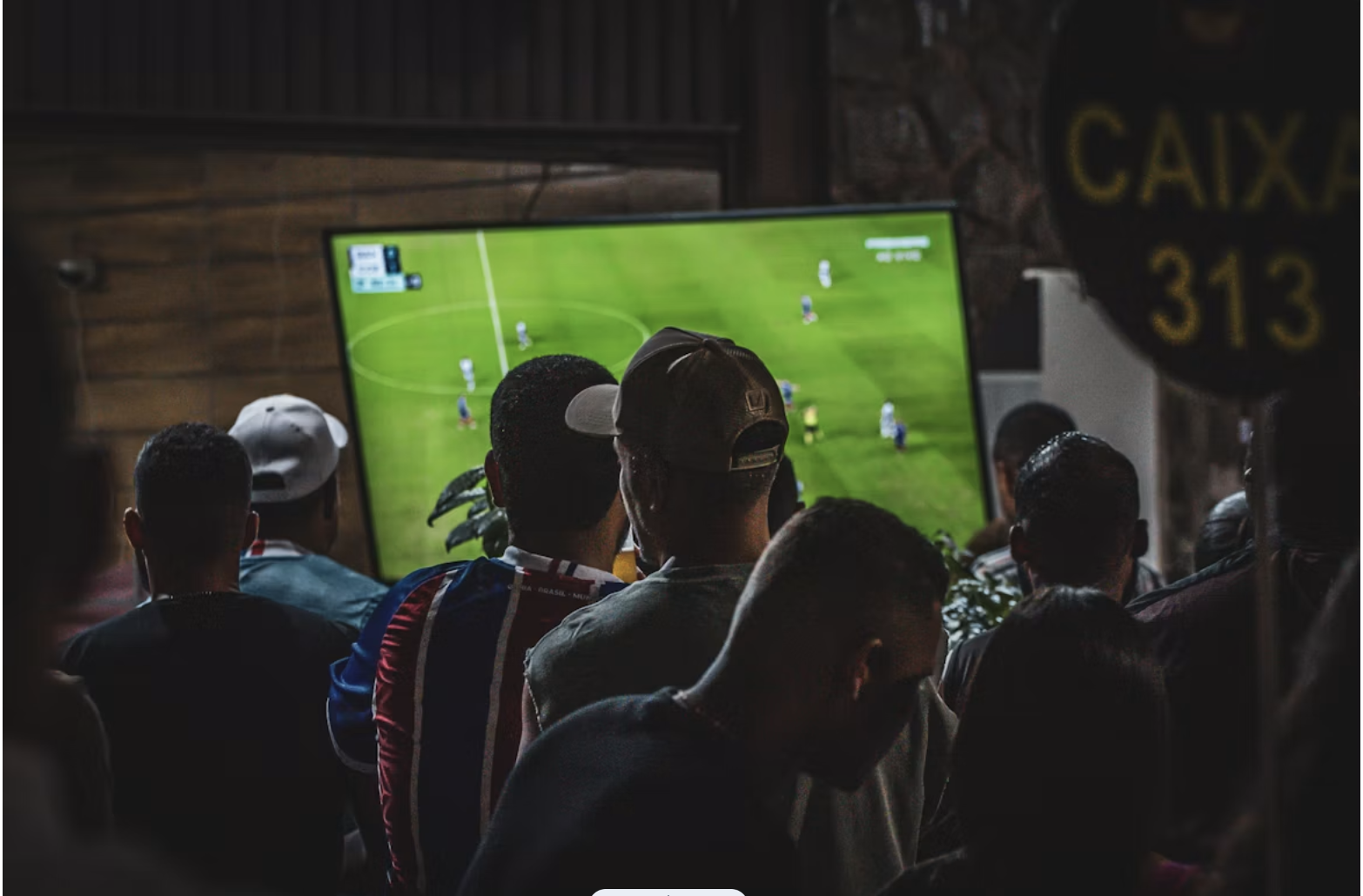 Alt: un groupe de personnes regardant un match de football à la télévision