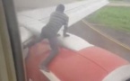 Un homme arrêté sur l'aile d'un avion peu avant le décollage