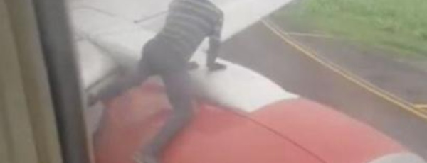 Un homme arrêté sur l'aile d'un avion peu avant le décollage